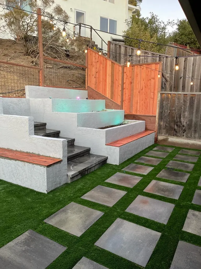 Concrete steps and stucco seat walls above pavers set in turf