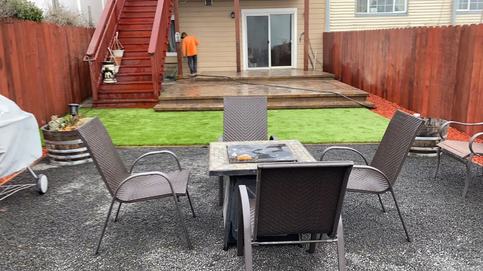 Gravel patio with fire table, turf and deck stairs