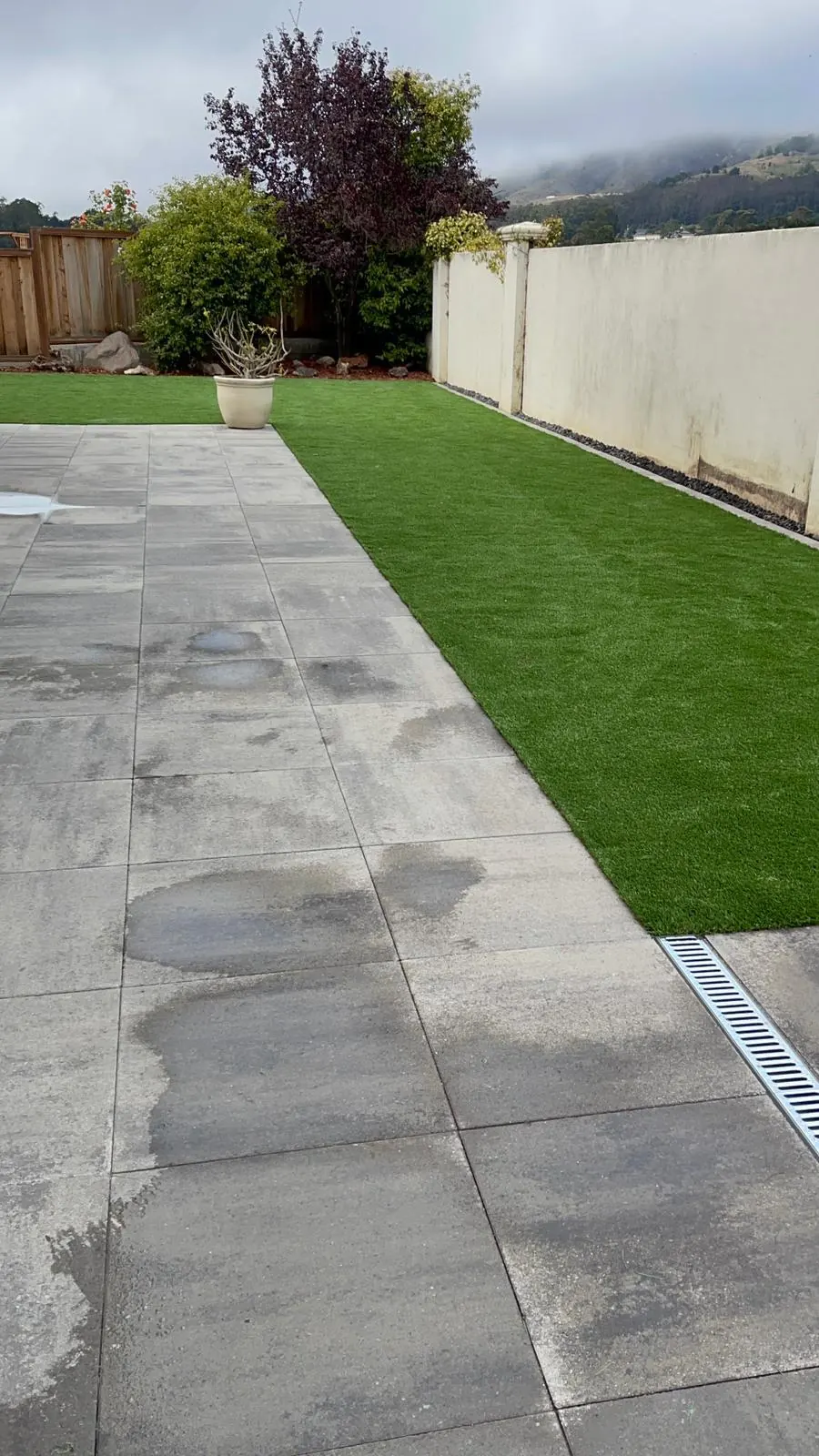 Large concrete pavers beside artificial turf with a channel drain