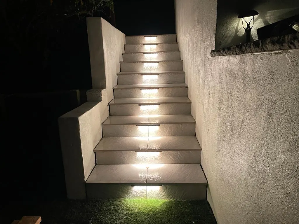 Concrete stairs with step lights between smooth stucco walls at night